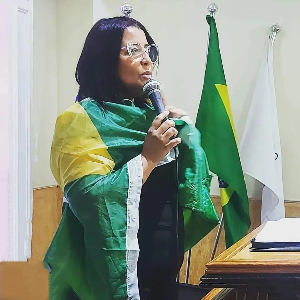 Luziléia com uma bandeira brasileira falando ao microfone