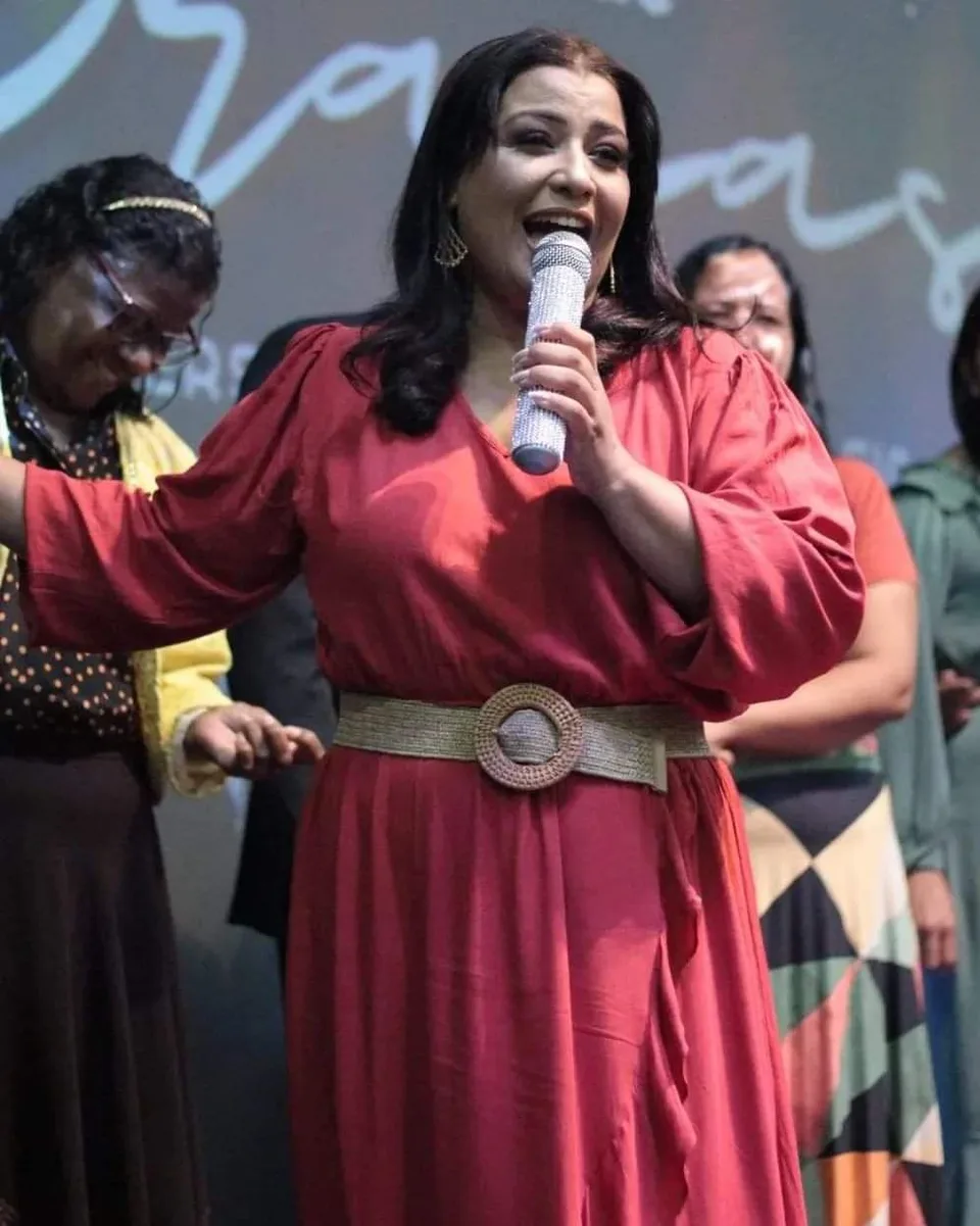 Luziléia de vestido vermelho falando ao microfone